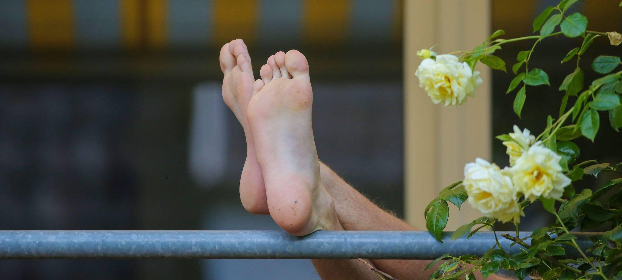 Die Füße eines Mannes sind auf einem Balkon zu sehen