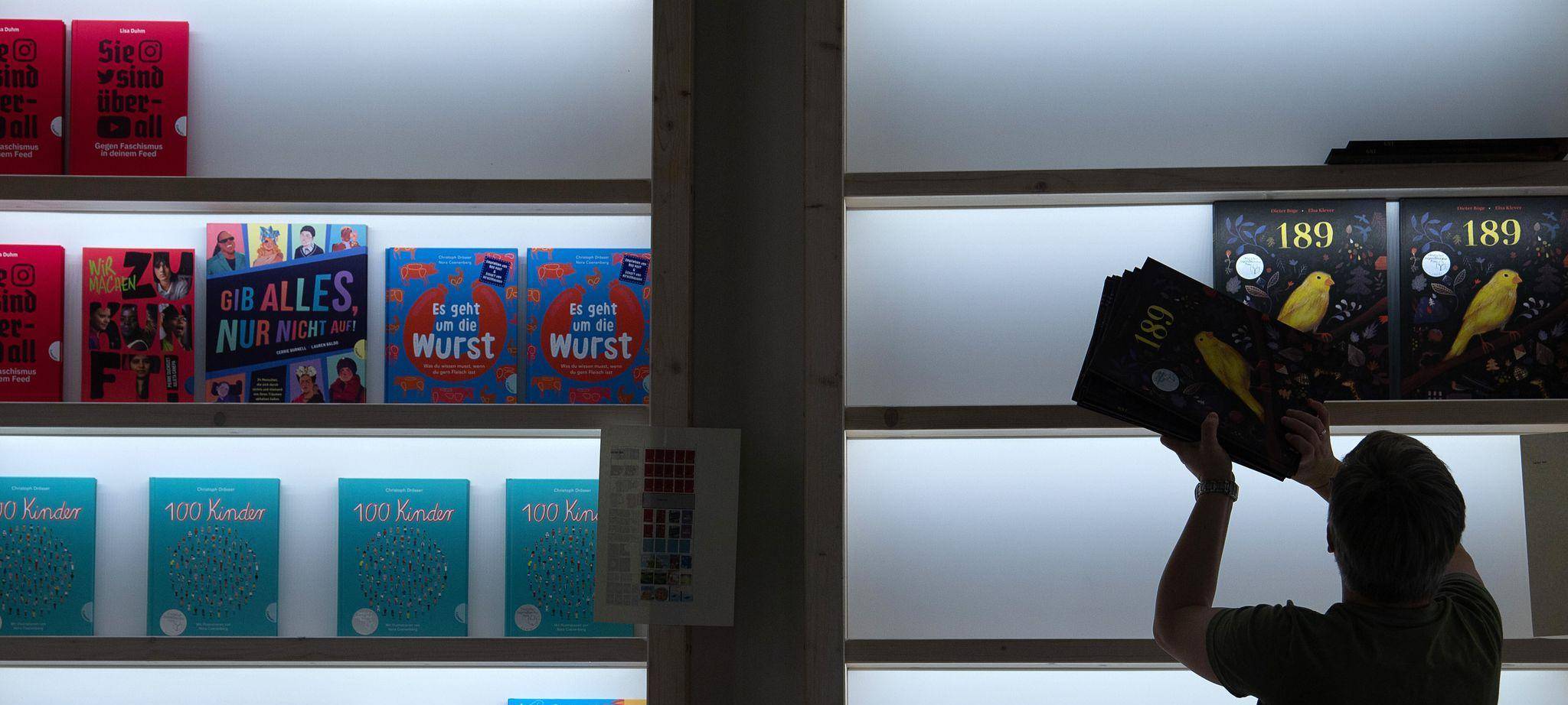 Frau räumt bei der Frankfurter Buchmesse Bücher in ein Regal